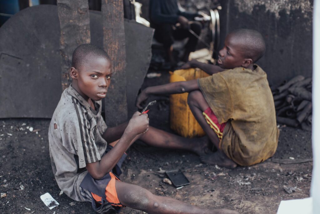 Two children working with tools in a rustic environment, illustrating child labor and hardships.
